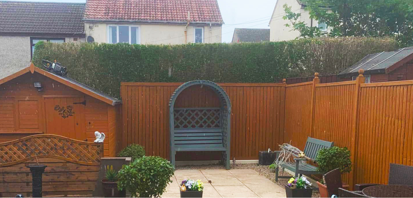 Neat garden with brown fence and shed and hedge cut back